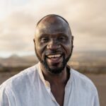 Happy African man smiling in camera on the beach during summer vacation