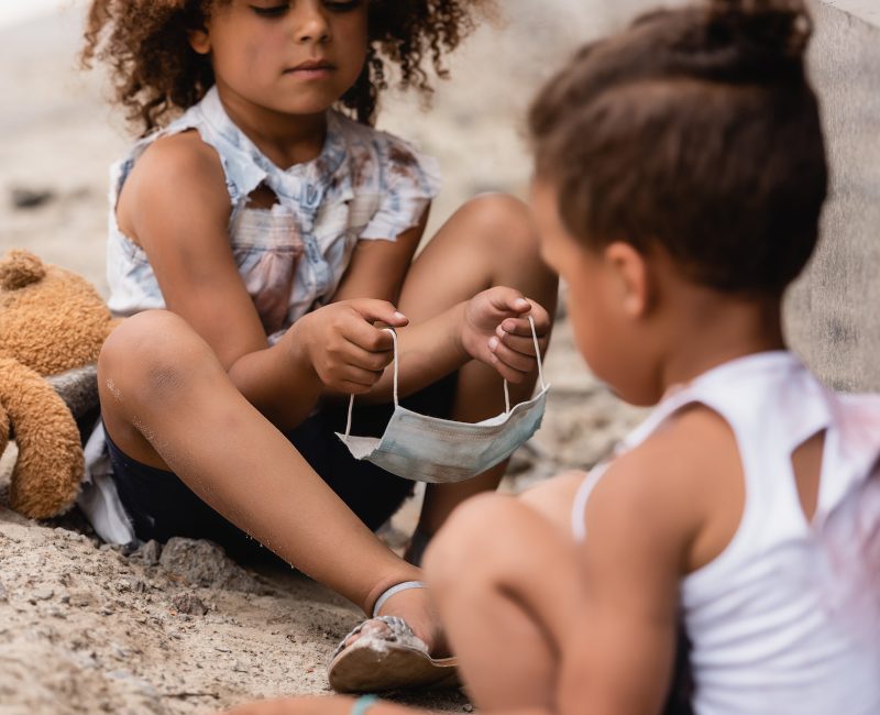 selective-focus-of-curly-african-american-child-holding-dirty-medical-mask-near-poor-brother-sitting.jpg